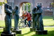 Fietsers aan beelden van Begijntjes in het Begijnhof Diest